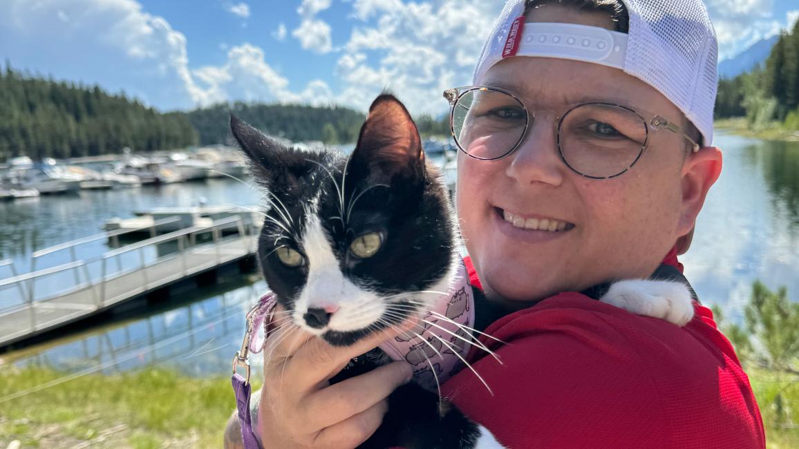 Lisa holding McMuffin the cat outside in front of a blue sky with clouds