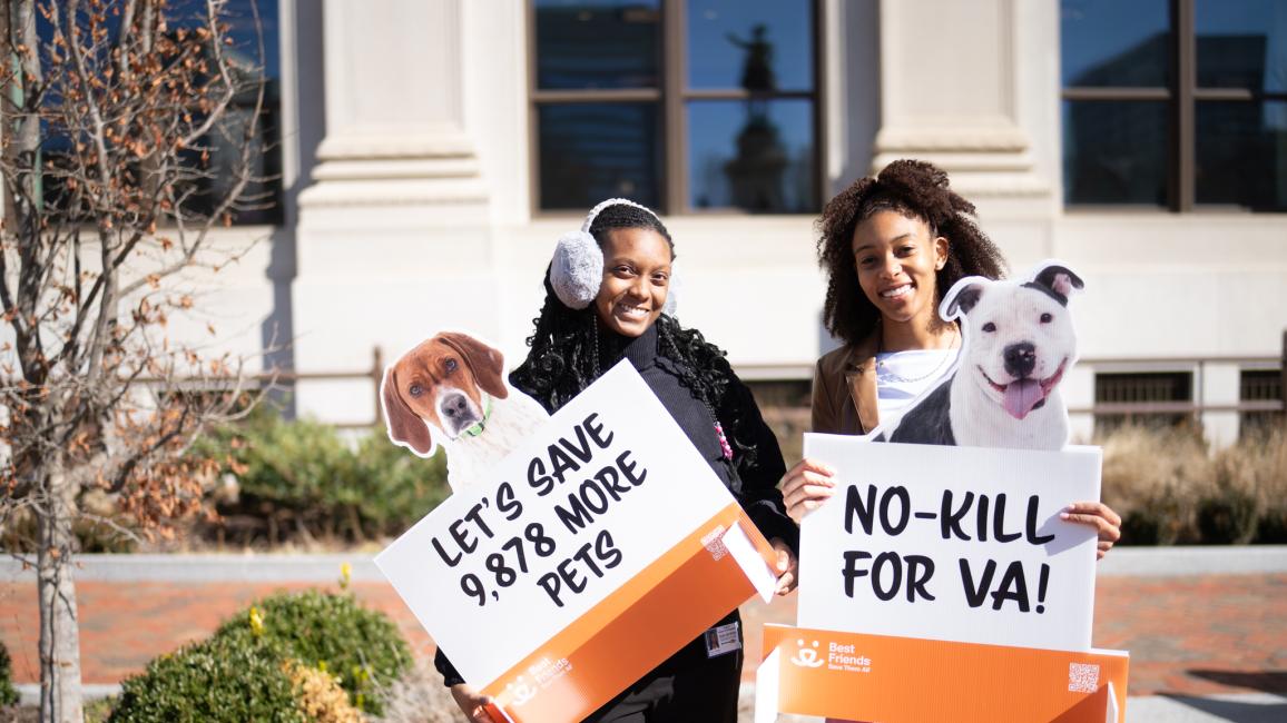 Two people outside holding signs at the Capitol in Richmond, Virginia